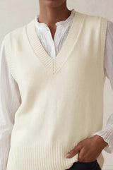 Model wearing the Aspiga Merino Wool V Neck Tank in Ivory, a fine-knit v-neck tank layered over a blouse, alternate view