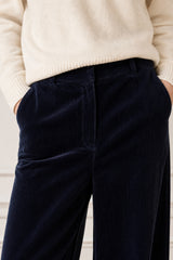 Close-up crop of a model wearing the Aspiga Wide Leg Chunky Corduroy Trouser in Deep Navy, hand in pocket