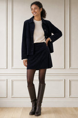Model wearing the Aspiga Corduroy Wrap Mini Skirt in Dark Navy, a wrap-style corduroy mini skirt with a button fastening, alternate view