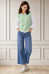 Model wearing the Aspiga Alpaca Blend Knitted Short Tank in Light Sage, a ribbed knit sweater vest layered over a white blouse, alternate view