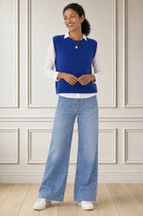 Model wearing the Aspiga Alpaca Blend Knitted Short Tank in Cobalt, a ribbed knit sweater vest layered over a white blouse, alternate view