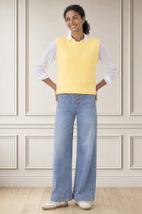 Model wearing the Aspiga Alpaca Blend Knitted Short Tank in Pale Yellow, a ribbed knit sweater vest layered over a white blouse, alternate view