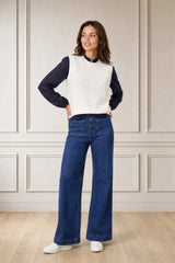 Model wearing the Aspiga Merino Wool Knitted Short Tank in Ivory over a navy lace blouse with jeans, hands on hips