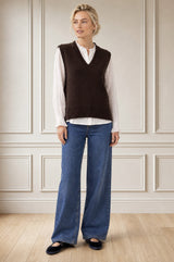 Model wearing the Aspiga Merino Wool V Neck Tank in Chocolate, a fine-knit v-neck tank layered over a blouse, alternate view