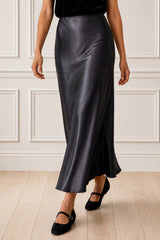Model wearing the Aspiga Satin Slip Skirt in Slate with a black halter top, back view, full-length