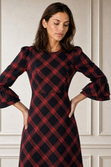 Close-up of a model wearing the Aspiga Elizabeth Check Dress in Red/Blue, hands on hips, looking down