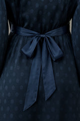 Close-up of the tie belt bow detail on the back of the Aspiga Satin Jacquard Spot Dress in Navy