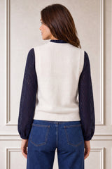 Model wearing the Aspiga Merino Wool Knitted Short Tank in Ivory over a navy lace blouse with jeans, back view