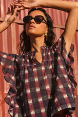 Close-up of a model wearing the Aspiga Danee Ikat Blouse in Wine, sunglasses, arms raised overhead outdoors