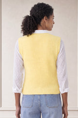 Additional styled photo of a model wearing the Aspiga Alpaca Blend Knitted Short Tank in Pale Yellow, a ribbed knit sweater vest layered over a white blouse