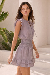 Model wearing the Aspiga Mini Macy Stripe Dress in Chocolate/White, a pinstriped mini dress with frill cap sleeves, a tie neck and a tiered ruffle hem, alternate view