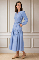 Model wearing the Aspiga Baby Cord Midi Dress in Ice Blue, a light blue corduroy belted shirt dress with long sleeves and a collar, alternate view