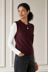 Model wearing the Aspiga Merino Wool Knitted Short Tank in Burgundy over a white top with black wide-leg trousers and white trainers