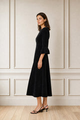 Close-up of the shoulder and ruffle cuff detail of the Aspiga Elizabeth Stretch Corduroy Midi Dress in Black, hand on hip