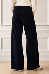 Model wearing the Aspiga Wide Leg Chunky Corduroy Trouser in Deep Navy with a cream jumper, back view