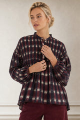 Close-up of a model wearing the Aspiga Mine Ikat Blouse in Wine, showing the button placket and pintuck yoke, hand at buttons