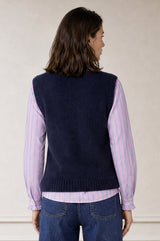 Additional styled photo of a model wearing the Aspiga Alpaca Blend Knitted Short Tank in Navy, a ribbed knit sweater vest layered over a striped blouse
