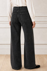 Model wearing the Aspiga Relaxed Straight Denim Jean in Black with a cream blouse, back view, full-length
