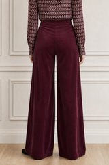 Additional styled photo of a model wearing the Aspiga Wide Leg Stretch Corduroy Trouser in Burgundy, a high-waisted wide-leg velvet corduroy trouser