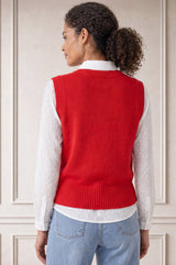 Additional styled photo of a model wearing the Aspiga Merino Wool Knitted Short Tank in Red, a ribbed knit crew-neck sweater vest layered over a white collared blouse
