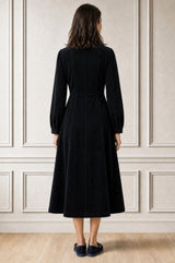 Additional styled photo of a model wearing the Aspiga A-Line Cord Dress in Navy, a corduroy button-front shirt dress with a collar, long sleeves and a tie waist