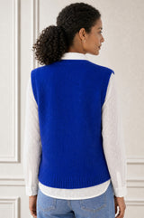 Additional styled photo of a model wearing the Aspiga Alpaca Blend Knitted Short Tank in Cobalt, a ribbed knit sweater vest layered over a white blouse