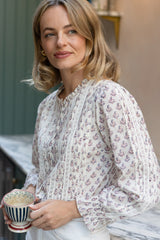 Close-up side view of a model wearing the Aspiga Vienna Printed Long Sleeve Blouse in Buta Pink/Cream, holding a teacup