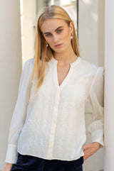 Close-up of a model wearing the Aspiga Rosemary Lace Front Blouse in Cream, showing the lace front panel and pearl drop earrings