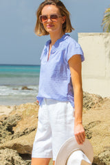 Baby blue Vanya blouse made from cotton with short sleeve, lace inserts and a v neckline, styled with Aspiga sunglasses and linen shorts