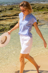 Baby blue Vanya blouse made from cotton with short sleeve, lace inserts and a v neckline, styled with Aspiga sunglasses and linen shorts