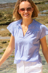 Baby blue Vanya blouse made from cotton with short sleeve, lace inserts and a v neckline, styled with Aspiga sunglasses and linen shorts
