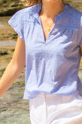 Baby blue Vanya blouse made from cotton with short sleeve, lace inserts and a v neckline, styled with Aspiga sunglasses and linen shorts