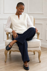 Lifestyle photo of a model wearing the Aspiga Merino Wool V Neck Tank in Ivory, a fine-knit v-neck tank layered over a blouse