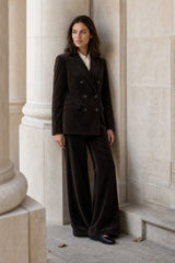 Lifestyle photo of a model wearing the Aspiga Wide Leg Chunky Corduroy Trouser in Chocolate Brown, a high-waisted wide-leg corduroy trouser with patch pockets