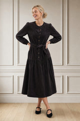 Model wearing the Aspiga Baby Cord Midi Dress in Chocolate, a chocolate brown corduroy belted shirt dress with long sleeves and a collar, front view