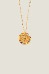 Close-up of the sun motif pendant and multicolour beaded surround of a gold necklace
