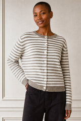 Model wearing the Aspiga Merino Wool Button Through Stripe Cardigan in Taupe/Cream with black trousers, front view, hand in pocket