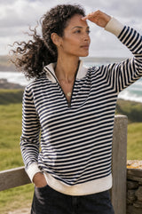 Lifestyle photo of a model wearing the Aspiga Merino Wool Stripe Quarter Zip Jumper in Off White/Navy, a breton-striped quarter-zip jumper