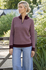 Lifestyle photo of a model wearing the Aspiga Merino Wool Stripe Quarter Zip Jumper in Burgundy/Pink, a striped quarter-zip jumper
