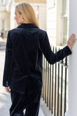 Model wearing the Aspiga Double Breasted Corduroy Blazer in Deep Navy with matching trousers, back view, hand resting on a white pillar